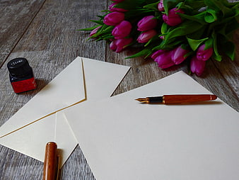 Fountain pen, ink, and pink tulips on wooden table