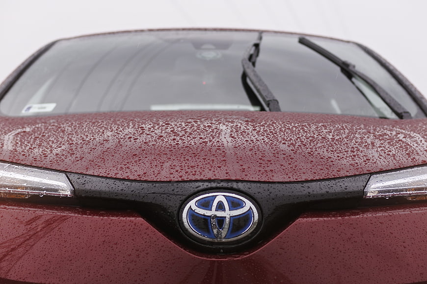 Close-up of Red Toyota C-HR Hybrid Front Emblem in Rain