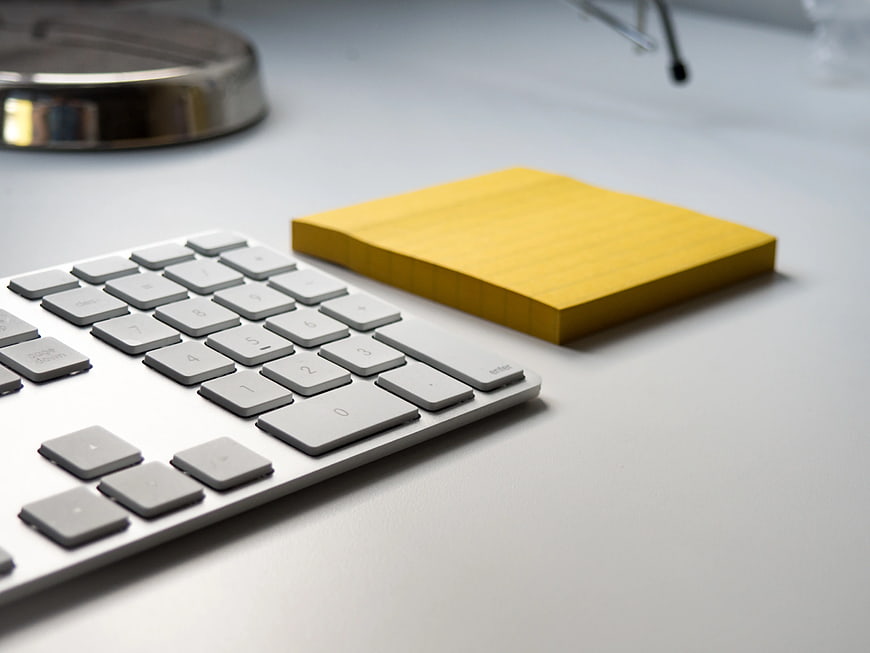 White Keyboard and Yellow Notepad on Clean Desk
