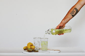 Hand Pouring Green Kiwi Banana Smoothie into Glass