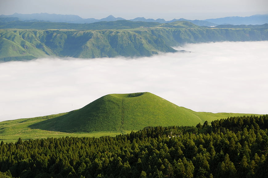 Lush Green Volcanic Cone Rising Above Sea of Clouds