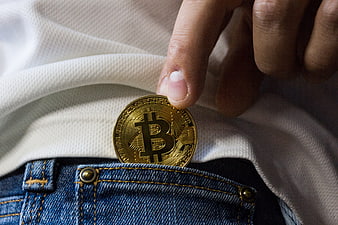 Hand Placing Gold Bitcoin Coin Into Denim Pocket