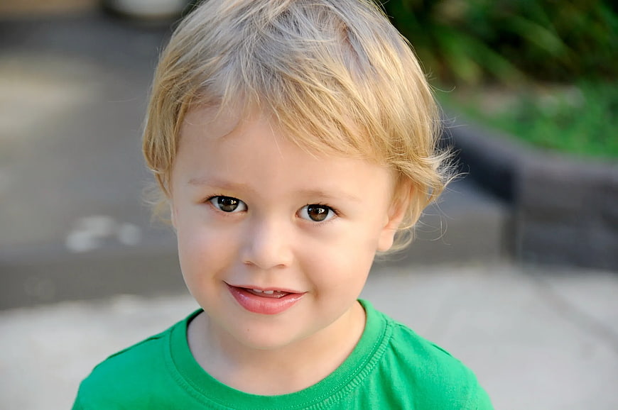 Close-up portrait of smiling blonde boy in green shirt