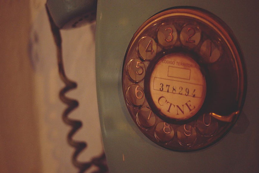 Close-up of vintage rotary dial telephone with coiled cord