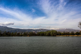 Serene Lake Landscape with Snow-Capped Mountains and Blue Sky