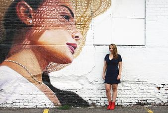 Woman in Blue Dress Standing by Large Street Art Mural