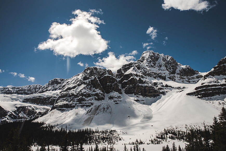Snowy mountain peaks under blue sky with clouds