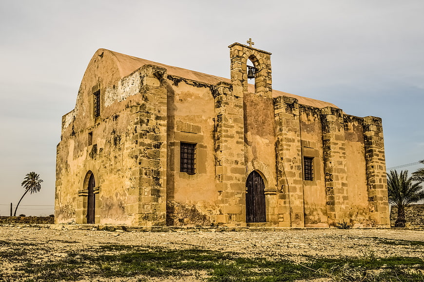 Ancient stone church in Cyprus with bell tower and palm trees