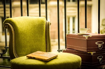 Vintage green armchair with book and suitcases on balcony