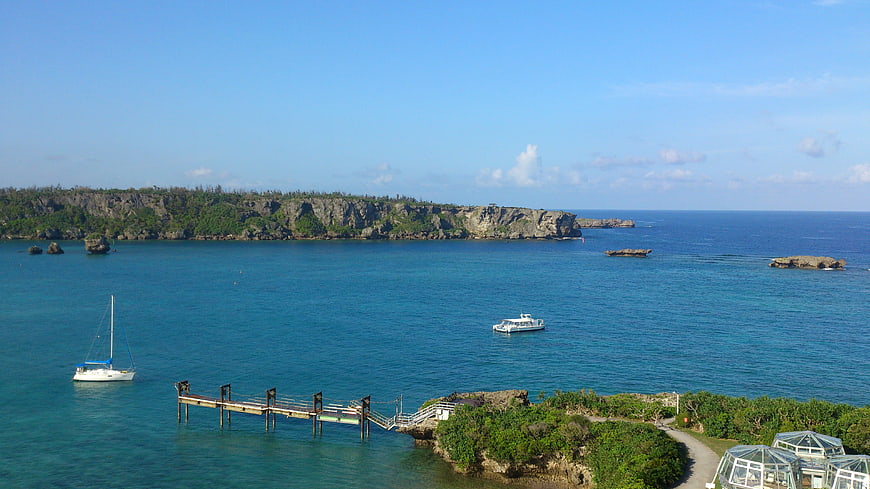 Tropical coastal landscape with pier, boats, and cliffs