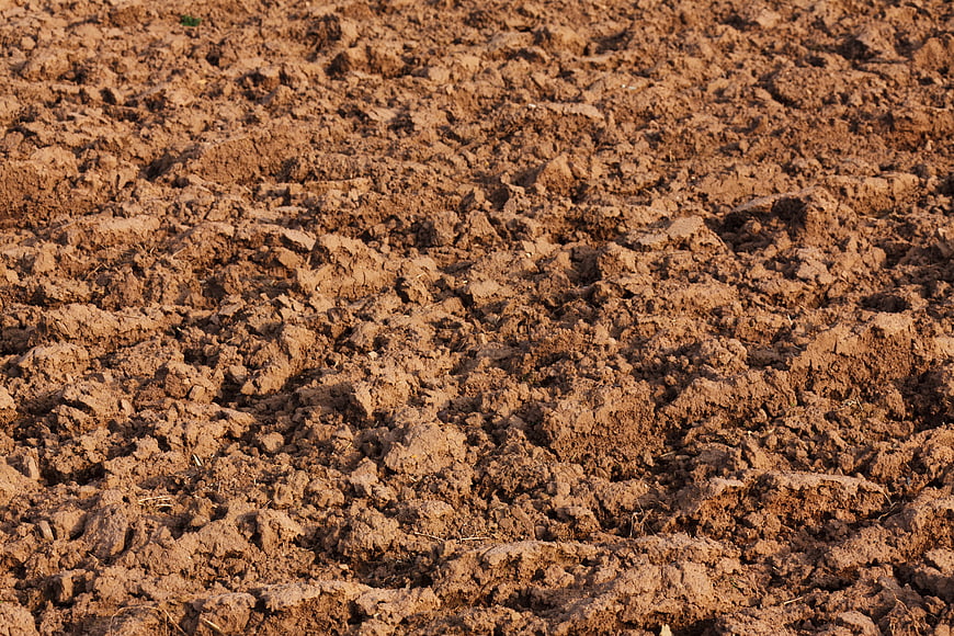 Close-up texture of tilled brown agricultural soil in a farm field