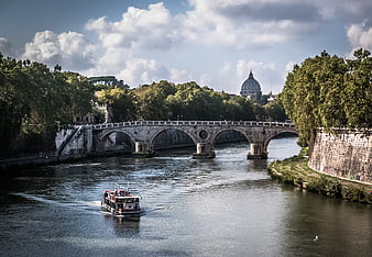Tourist boat on Tiber River with St. Peter's Basilica in Rome