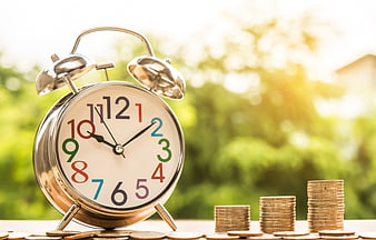 Vintage Alarm Clock And Coin Stacks On Wooden Table