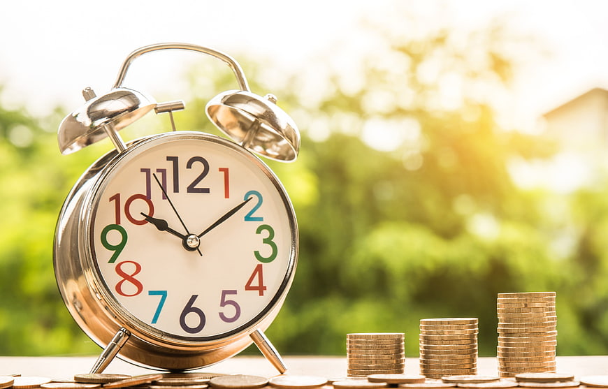 Vintage Alarm Clock And Coin Stacks On Wooden Table