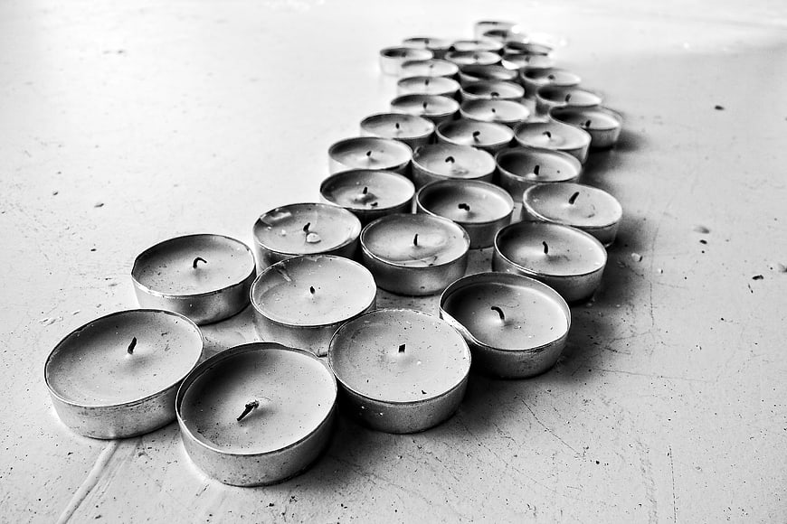 Black and white photo of unlit tea light candles arranged in a row