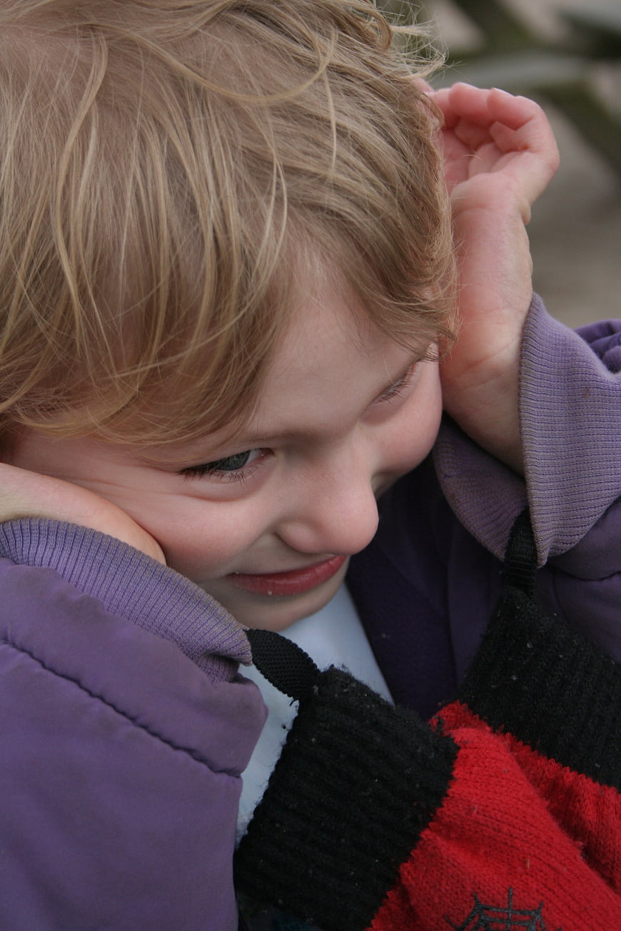 Close-up of young child covering ears in distress