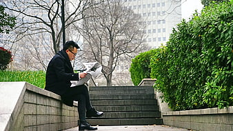 Man reading newspaper on urban park steps