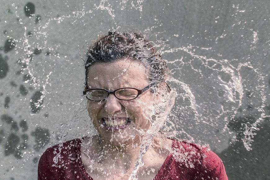 Woman with glasses getting splashed by water