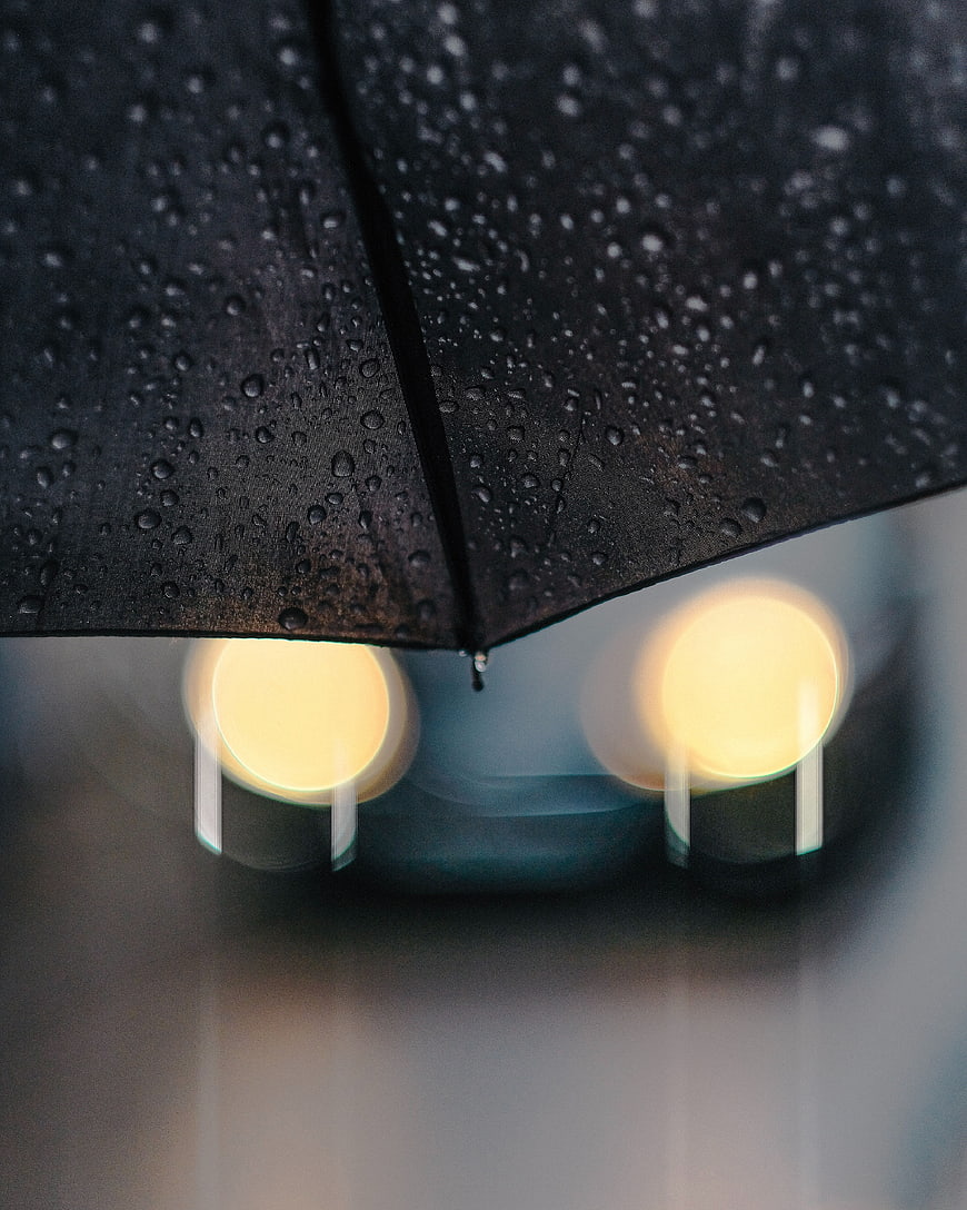 Black umbrella with raindrops and blurred city lights