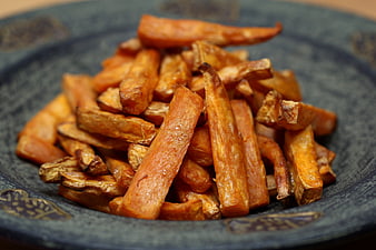 Crispy roasted sweet potato fries in a rustic dark bowl