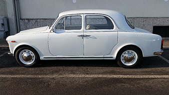 Side view of a classic white vintage sedan parked on asphalt