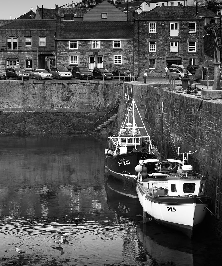 Black and white fishing boats in a stone harbor