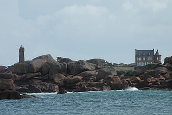 Lighthouse and house on rocky coast in Brittany, France