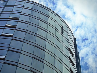 Modern curved glass office building facade against blue sky