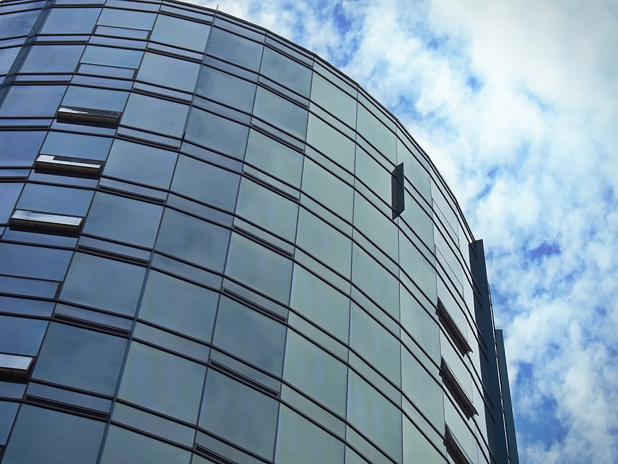 Modern curved glass office building facade against blue sky