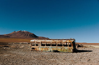 Rusty abandoned bus in desert landscape with mountains