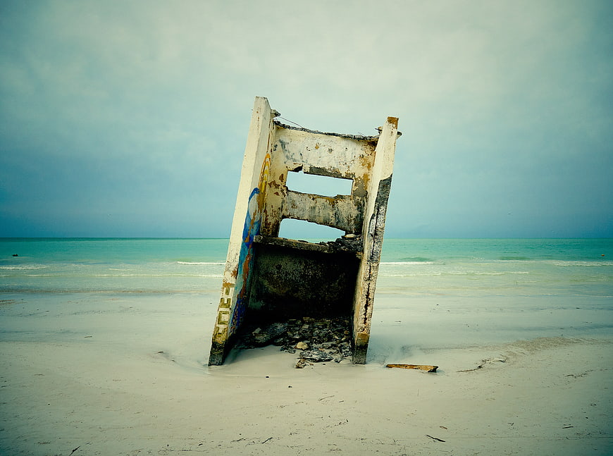 Abandoned Concrete Structure on Sandy Beach with Ocean Background