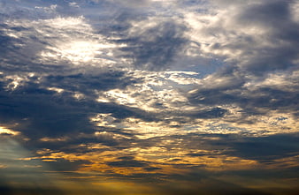 Dramatic sunset sky with golden sun rays through clouds