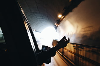 Hand reaching out of car window in tunnel