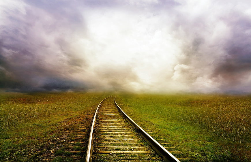 Dramatic Railway Tracks Leading to Stormy Sky in Green Field