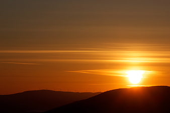 Golden Sunset Over Silhouetted Mountain Range with Wind Turbines