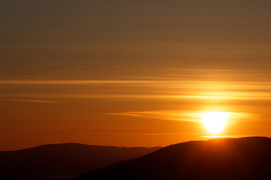 Golden Sunset Over Silhouetted Mountain Range with Wind Turbines