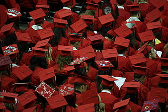 Crowd of graduates in red caps and gowns from behind