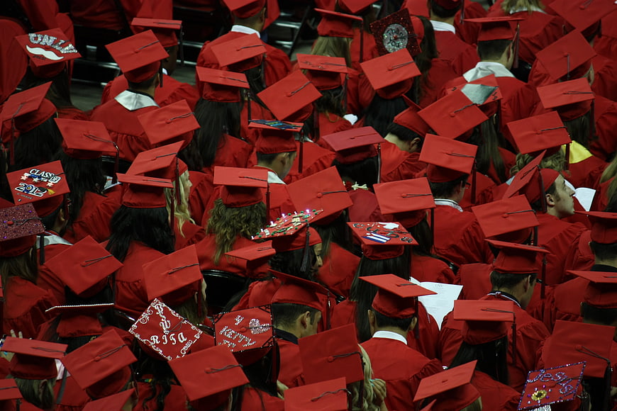 Crowd of graduates in red caps and gowns from behind