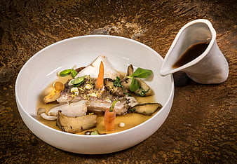 Gourmet fish dish with mushrooms and carrots in white bowl