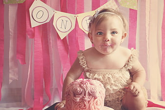 Cute baby girl with frosting on face at first birthday party