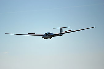White glider soaring in clear blue sky