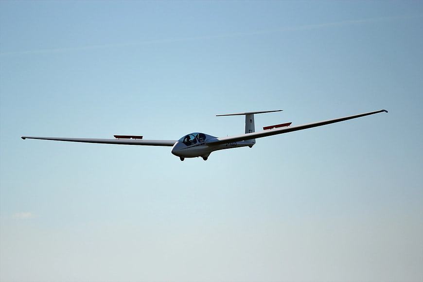 White glider soaring in clear blue sky