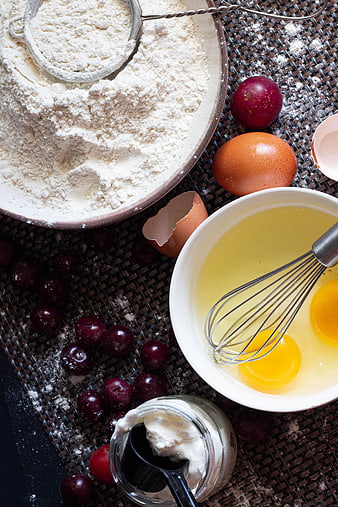Top view of baking ingredients with flour, eggs, and cherries