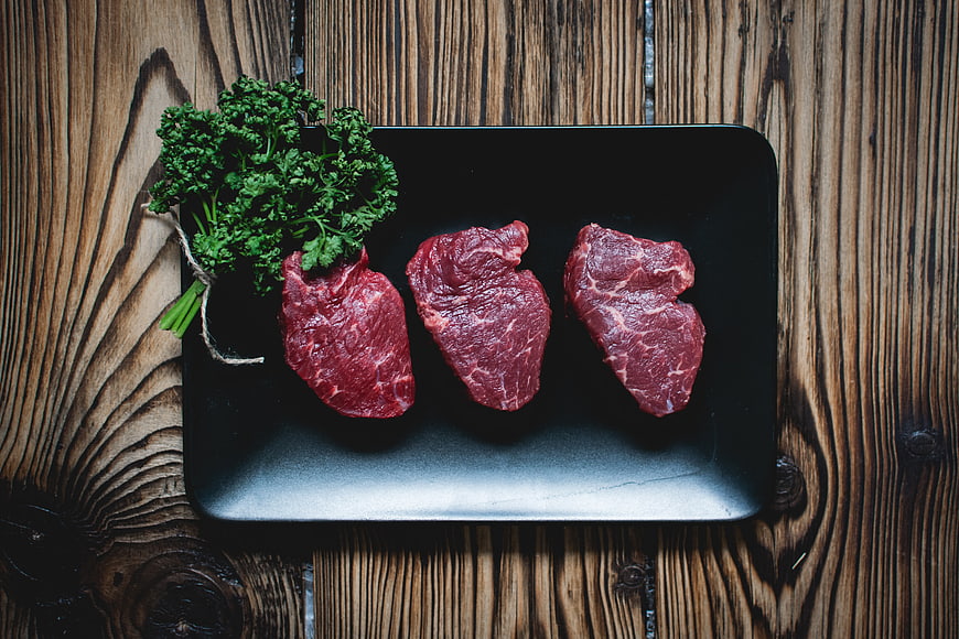 Raw Beef Steaks on Black Plate with Parsley
