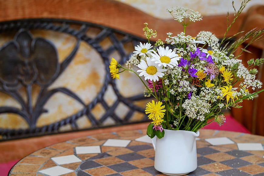Colorful wildflower bouquet in white ceramic pitcher on tiled table