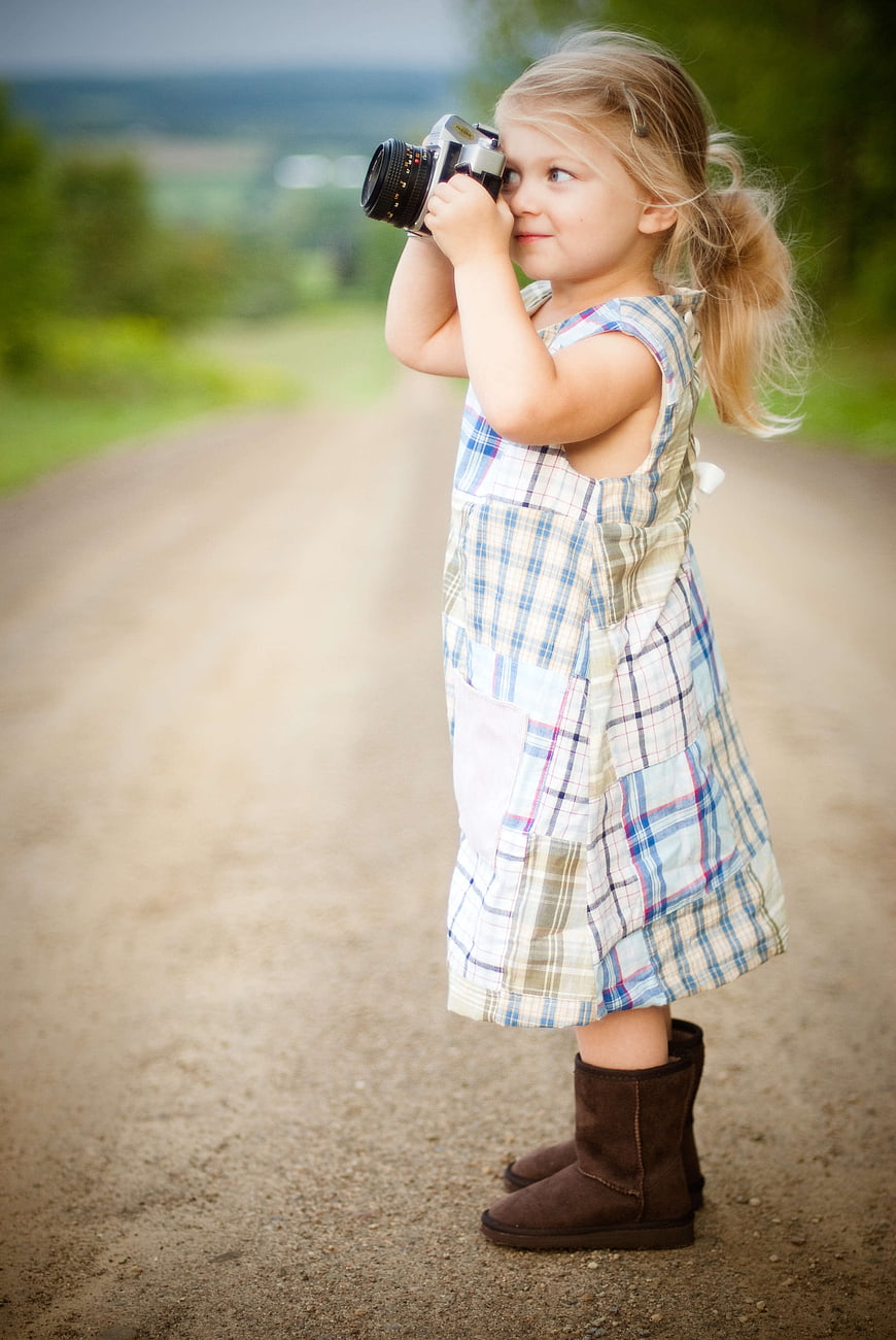 Little girl with vintage camera on country road