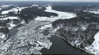 Aerial view of frozen river with ice floes in winter forest