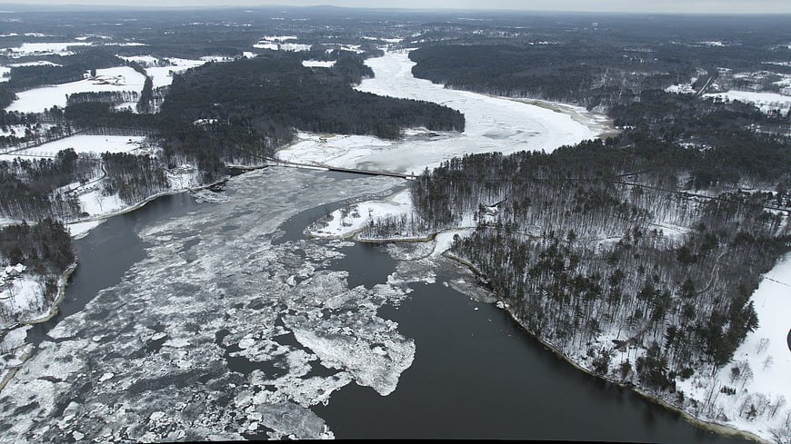 Aerial view of frozen river with ice floes in winter forest