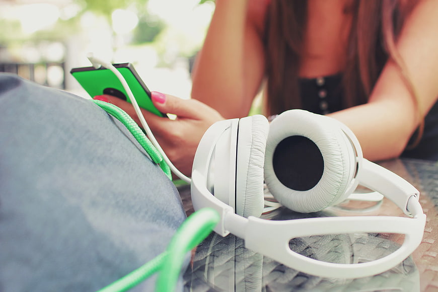 White Headphones and Green Smartphone on Table