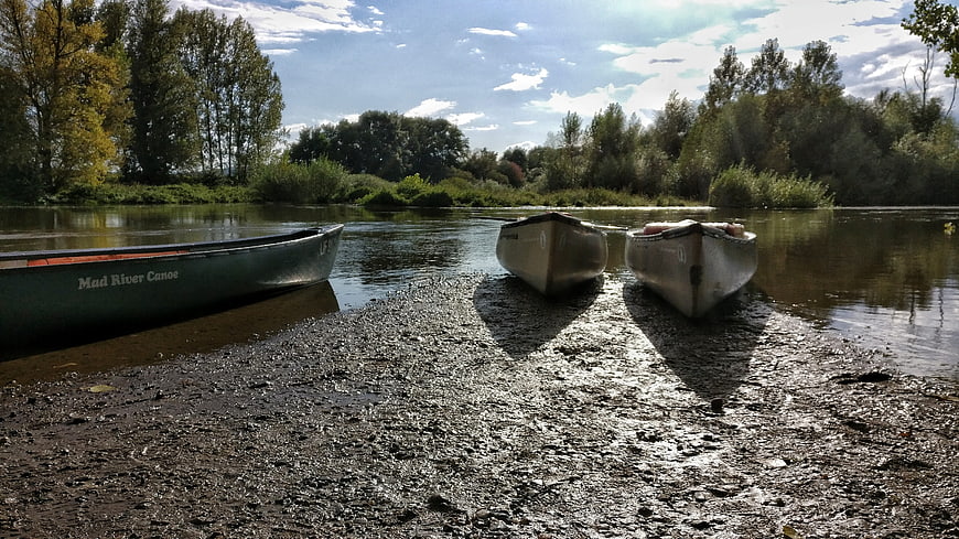 Three Canoes Resting on a Muddy Riverbank
